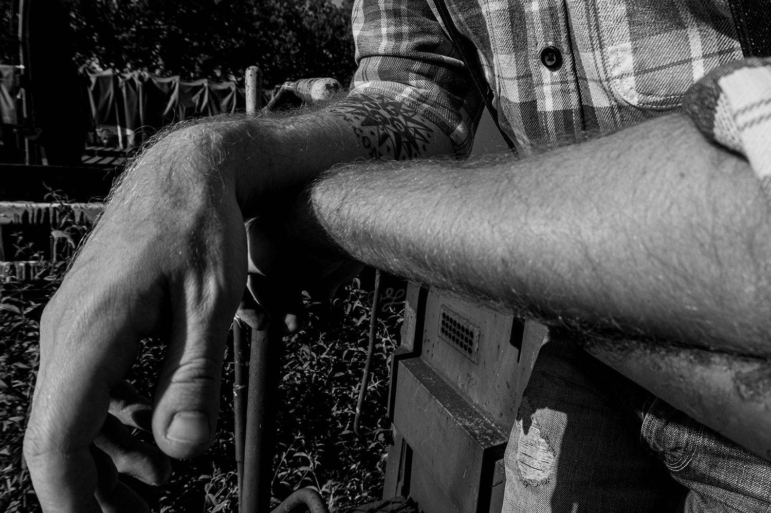 Photographie noir et blanc des bras croisés d'un modèle homme sur une rembarde métallique